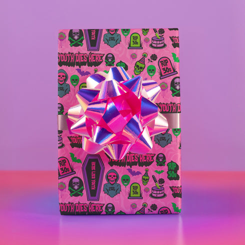 40th birthday Vibrant wrapping paper featuring a playful goth theme with illustrations of skulls, birthday cakes, and caskets marked "RIP 30s", set against a pink background with green accents. Ideal for themed 40th birthday gifts.